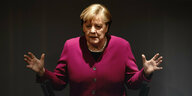 Angela Merkel hebt ihre Hände hoch.