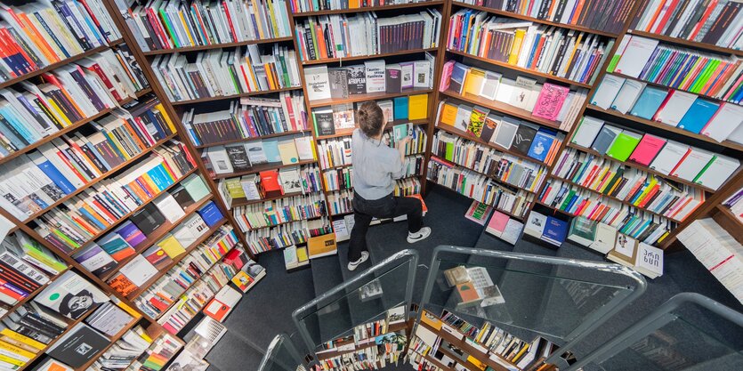 Eine rundgeschwungene bunte Bücherwand, davor eine junges Mädchen