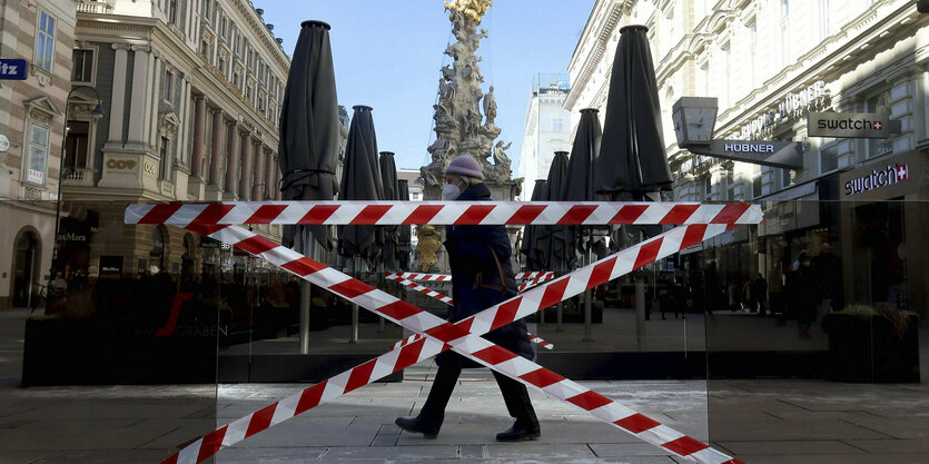 Eine Fußgängerin geht an abgesperrten Bereichen vor Cafés in Wien vorbei