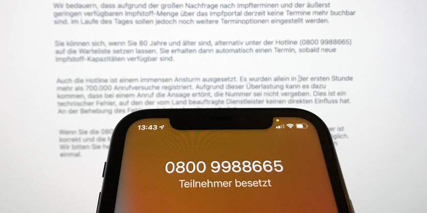 Bildschirm eines Smartphones mit der Nummer der Impfhotline und dem Vermerk Teilnehmer besetzt.