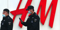 Zwei chinesische Polizisten vor dem Logo von H&M