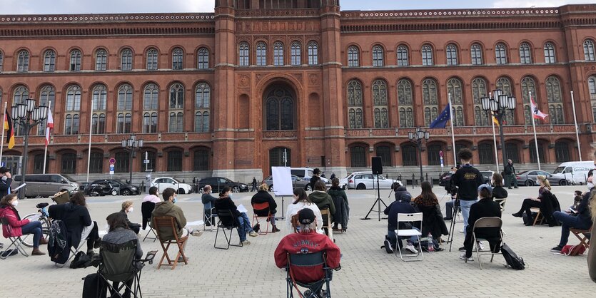 Menschen sitzen vor dem Roten Rathaus