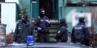 Einsatzkräfte der Bremer Polizei stehen vermummt und gerüstet vor einem Hauseingang