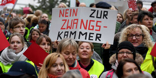 Demonstrit:innen halten ein Schild hoch, auf dem steht: "Niein zur Zwangskammer!"