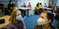 Kinder mit Masken in einer vollbesetzten Grundschulklasse