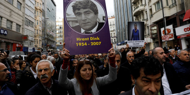 Eine Menschenmenge läuft auf einer Straße und hält ein Plakat mit dem Foto von Hrant Dink in die Höhe