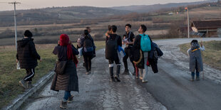 Menschen sind von hinten zu sehen wie sie eine Straße langlaufen