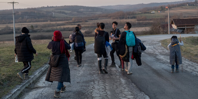 Menschen sind von hinten zu sehen wie sie eine Straße langlaufen