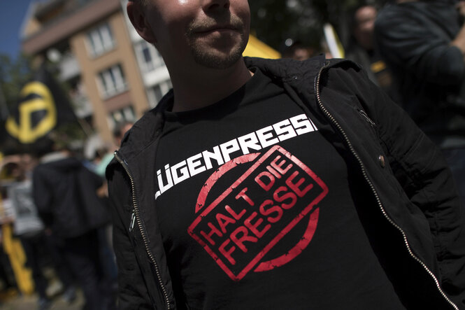 Ein Mann trägt ein T-Shirt mit der Aufschrift Lügenpresse halt die Fresse