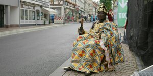 König Bansah sitzt in königlicher Kleidung in der Stadt auf seinem Thron