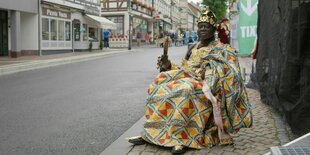 König Bansah sitzt in königlicher Kleidung in der Stadt auf seinem Thron