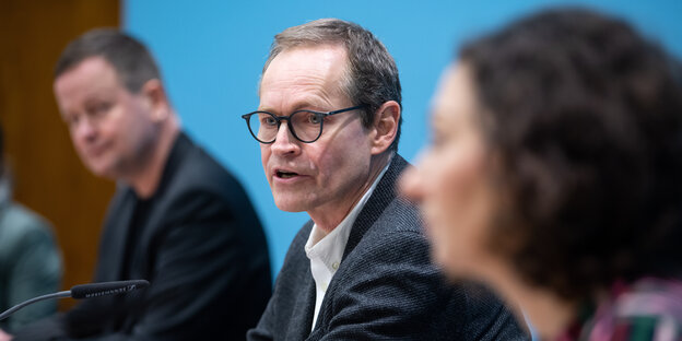 Michael Müller sitzt zusammen mit Klaus Lederer und Ramona Pop bei einer Pressekonferenz