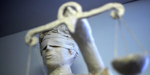 Eine Statue mit verbundenen Augen, in der Hand hält Justitia eine Waage.
