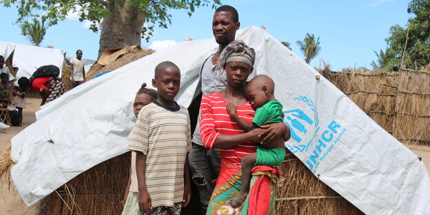 Eine Famile sus Mosambik steht vor einem Zelt