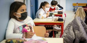 Kinder mit Maske in einem Klassenraum.