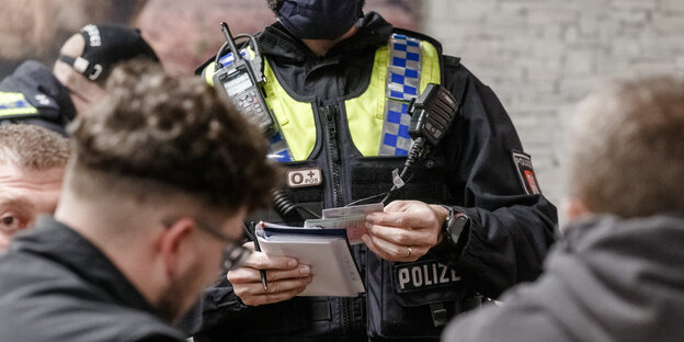 Polizisten kontrollieren in einer Bar die Papiere von jungen Männern.