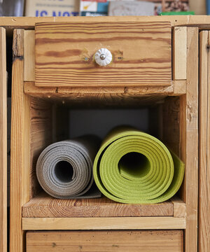 Zwei Yogamatten liegen in einem Fach eines Holz-Schranks Zwei Yogamatten liegen in einem Fach eines Holz-Schranks
