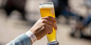 Eine Hand mit einem vollen Weizenglas und einem Tagesticket-Armband von Tübingen