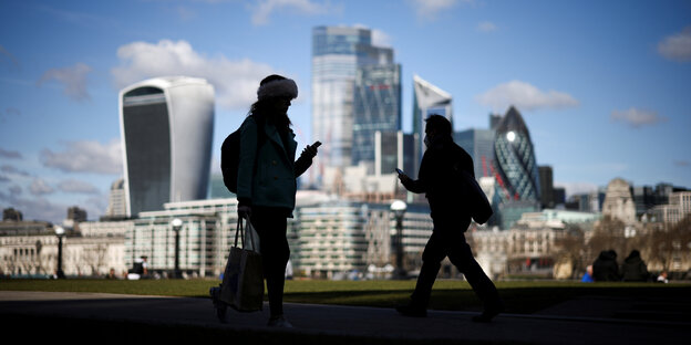 Zwei Menschen im Schattenriss mi tihren Smartphones vor Londoner Kulisse