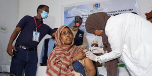 Eine Frau mit Kopftuch erhält eine Impfung via Spritze