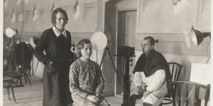 Eine junge Frau, Dora Maria Kahlich, steht hinter einem sitzenden Mädchen in einem Fotoatelier
