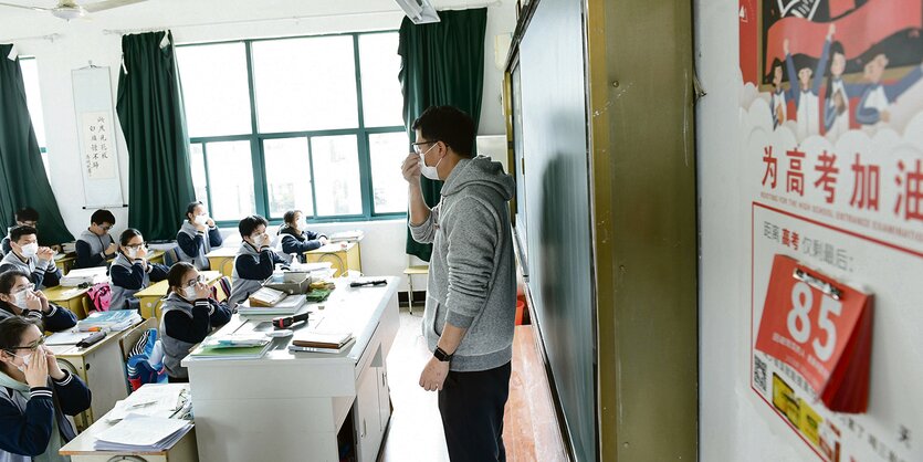 Lehrer vor Klasse, alle mit Mund-Nasen-Masken.