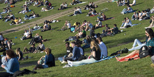 Menschen sonnen sich auf einer Wiese gedrängt