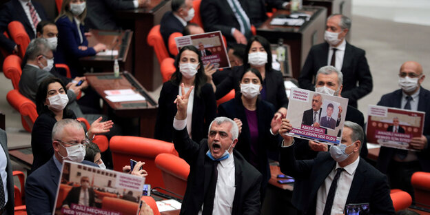 Abgeordnete protestieren mit Plakaten und erhobenen Händen