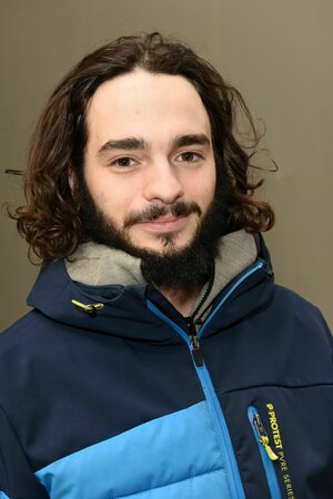 Ein junger Mann mit langen Haaren und Bart blickt in die Kamera Ein junger Mann mit langen Haaren und Bart blickt in die Kamera