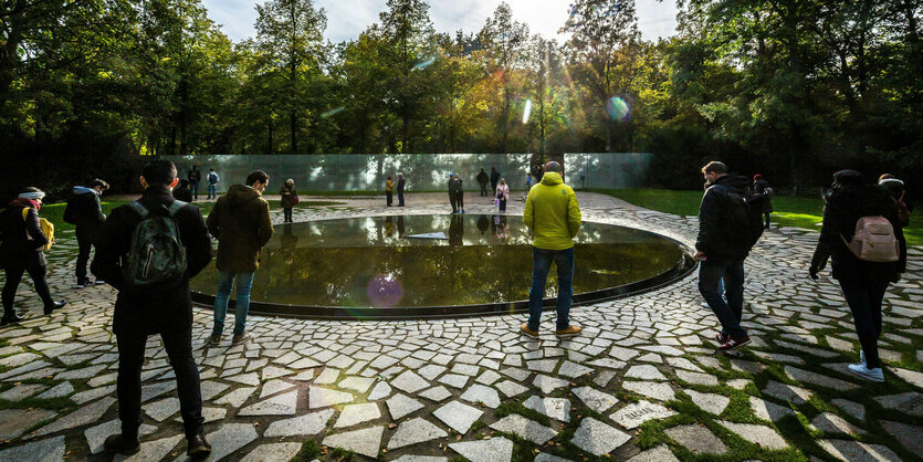 Menschen stehen vereinzelt umd das Mahnmal im Tiergarten