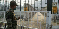 Soldat blick durch ein Gitter auf eine Grenzbrücke.