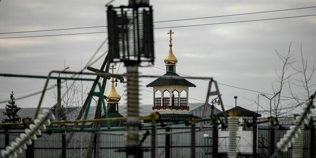 Dei vergoldete Kuppel einer orthodoxen Kirche hinter Gefängniszäunen