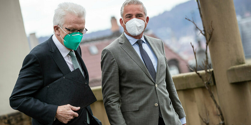 Kretschmann (l.) und Strobl, beide mit Mund-Nasenschutz draußen auf einer Terrasse . Sie unterhalten sich im Gehen.