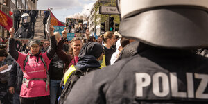 Demonstrierende in Stuttgart gegenüber einer behelmten Einsatzkraft der Polizei