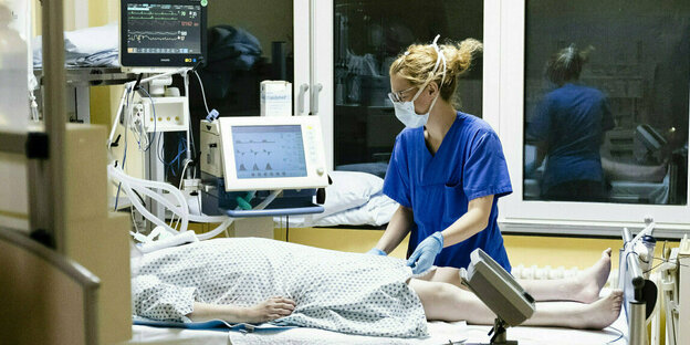Eine Krankenschwester steht am Bett einer Coronapatientin