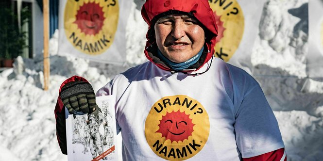 ein Demonstrant mit roter Kapuze und "uran?Nein, danke"-T-Shirt hält ein Flugblatt in der Hand