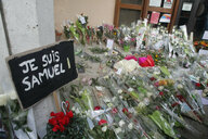 Blumen liegen neben einem Schild mit der Aufschrift "Je suis Samuel!"