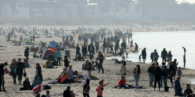 Menschen liegen und sitzen an einem Strand