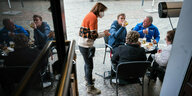 Wirtin bringt ihren Gästen, die vor ihrer Kneipe in der Innenstadt von Saarbrücken sitzen, Getränke