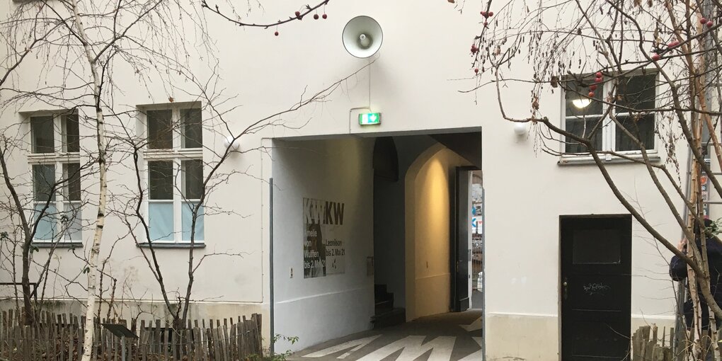 Ein weißer Tütenlautsprecher ist auf dei weiße Wand über dem Hofeingang zu den KW Institute for Contemproary Art angebracht. Der Lautsprecher fällt kaum auf.