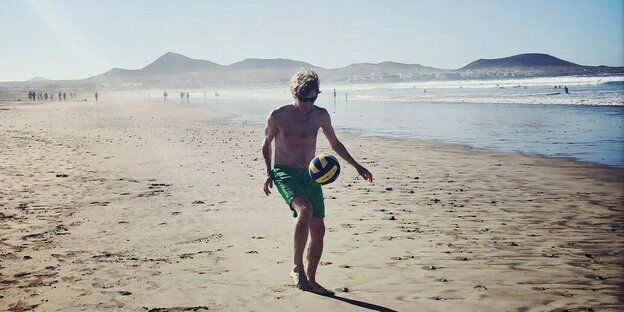 Ein Mann beim Fußballspielen am Strand