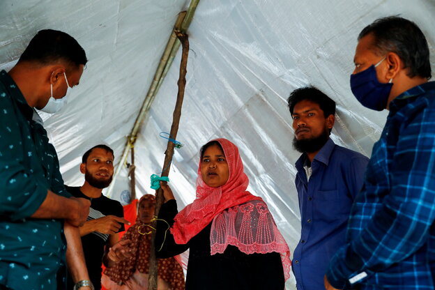 Mehrere Flüchtlinge stehen unter einer Zeltplane und reden miteinander.