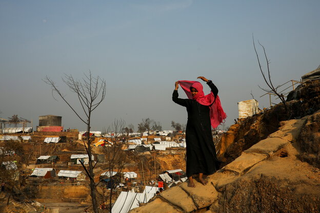 Eine Frau mit Schal steht am Hang eines Flüchtlingscamps.