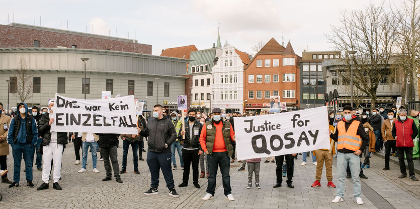 Menschen stehen auf einem Platz und halten Transparente mit den Aufschriften "Das war kein Einzelfall" und "Justice fpr Qosay"