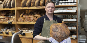 Dirk Steiger Inhaber von Zeit für Brot steht in seiner Filiale in der Schönhauser Allee 144 und hält eines seiner Brote in den Händen