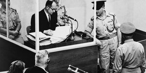 Schwarzweiß Aufnahme des Prozesses gegen Adolf Eichmann, mit dem Beklagten im Zeugenstand