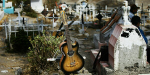 Eine Gitarre steht neben einem Grabstein auf einem mexikanischem Friedhof