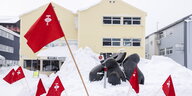 Rote Fahnen der Inuit Partei stecken im Schnee