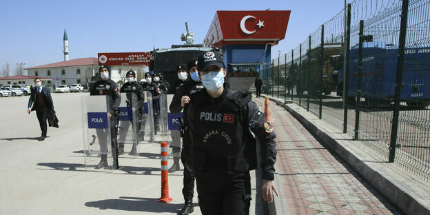 Polizisten und Polizistinnen bewachen das Gerichtsgebäude mit türkischer Nationalflagge als Fassade