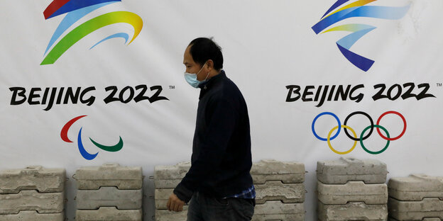 Ein Mann läuft an Logos für die Olympischen Winmterspiele in Peking vorbei